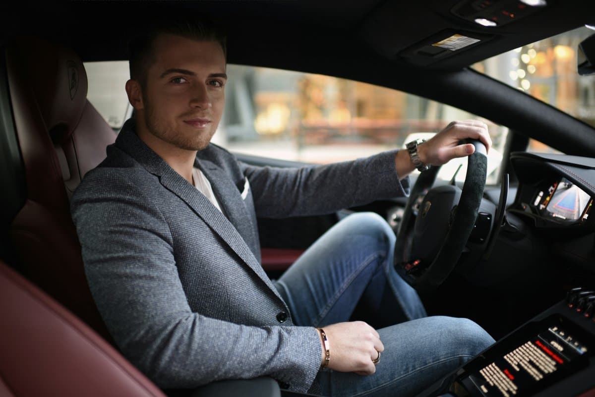 Austin Zelan seated in the driver's seat of a Lamborghini, one hand on the wheel