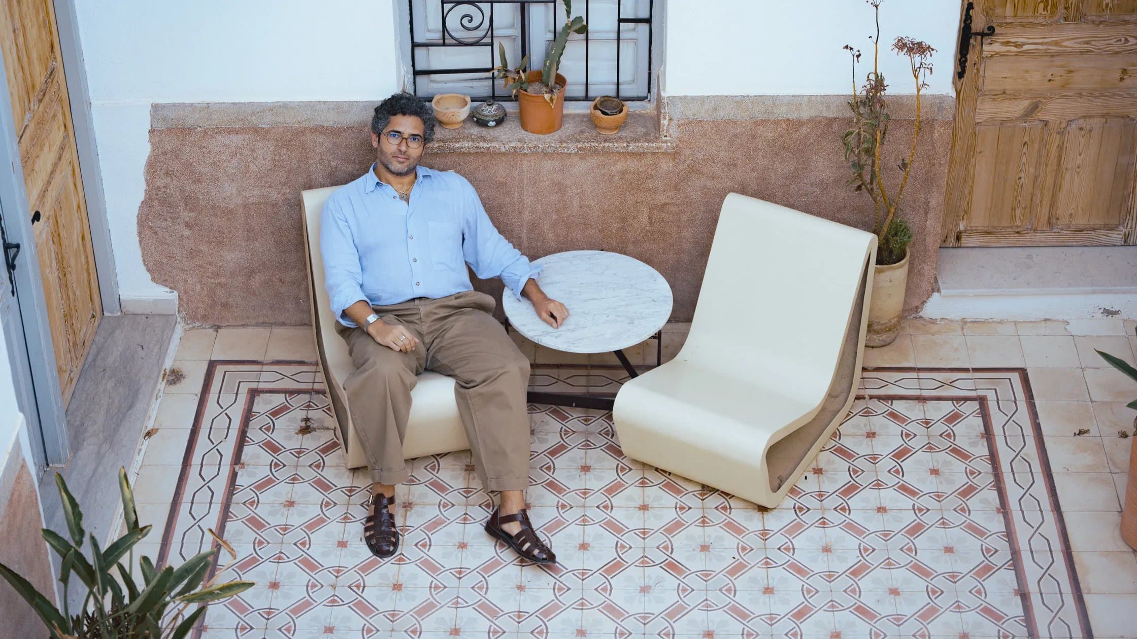 Faissel El-Malak seated in a courtyard in Sousse, Tunisia, beside a custom cream-colored chair