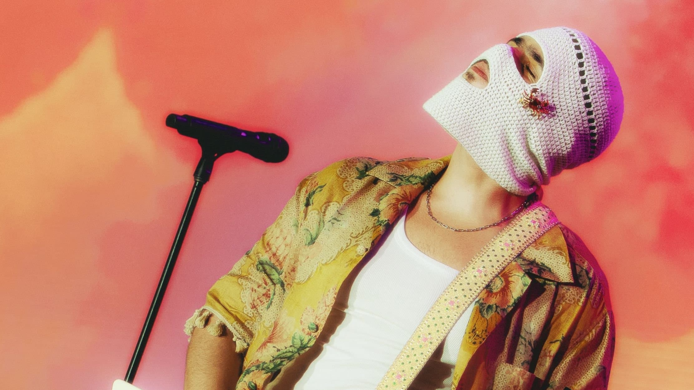 A performer on stage wearing a yellow floral shirt and red trousers