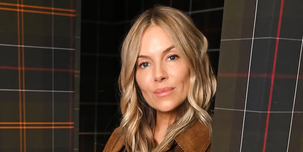 Sienna Miller wearing a brown corduroy jacket, peeking between two tartan-patterned panels